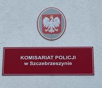 dwie tabliczki na budynku, jedna z godłem Polski druga z napisem Komisariat Policji w Szczebrzeszynie