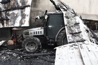 ciągnik rolniczy pod zawalonym dachem strawionej ogniem hali magazynowej