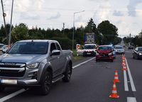 Na drodze stoją pojazd marki Isuzu i za nim osobowe suzuki. W tle na poboczu zaparkowany samochód służby drogowej.