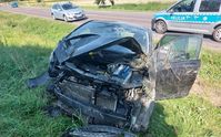Stojący w przydrożnym rowie uszkodzony w wyniku zderzenia z innym pojazdem osobowy Opel. W tle policyjny radiowóz.