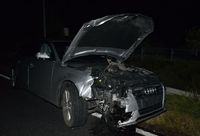 Audi osobowe stoi na poboczu drogi. Ma uszkodzony przód w wyniku zderzenia z innym pojazdem.