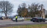 policjant stojący na drodze wskazuje kierowcy auta kierunek jazdy