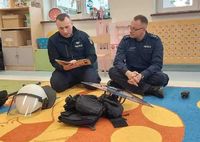 policjanci na spotkaniu w przedszkolu czytają dzieciom książkę