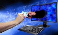 dłoń wychodząca z ekranu komputera trzymająca kartę kredytową