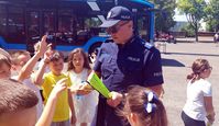 policjant rozdaje dzieciom odblaskowe opaski