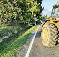 miejsce zdarzenia drogowego, ciągnik rolniczy stojący na drodze i w oddali motocykl w rowie