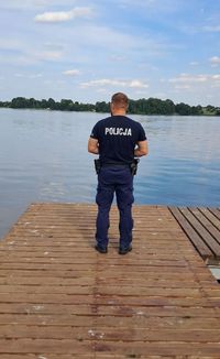 policjant stoi na pomoście nad wodą