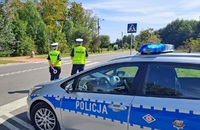 policyjny radiowóz i dwoje policjantów stojących na poboczu drogi