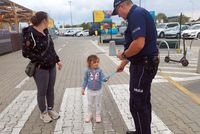 policjant przekazuje dziecku element odblaskowy