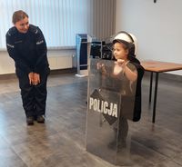 policjantka i ubrane w policyjną kamizelkę, kask ochronny i pałkę dziecko