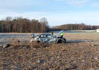 Uszkodzone osobowe BMW w polu, obok niego dwaj policjanci