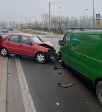 Na zdjęciu znajdują się dwa samochody, czerwony Fiat i zielony Opel dostawczy. Samochody są uszkodzone po zderzeniu.