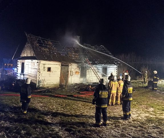 strażacy w czasie akcji gaśniczej płonącego drewnianego domu