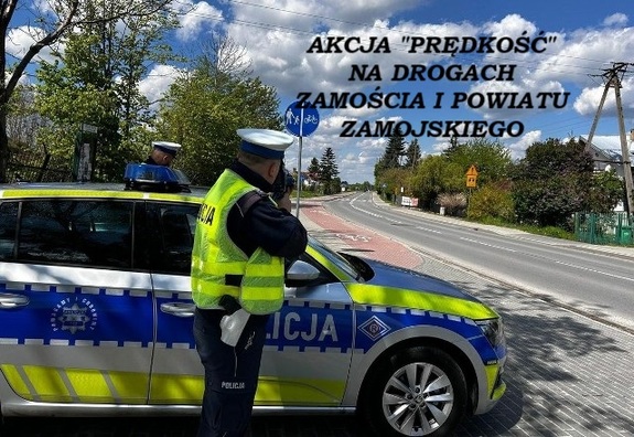 policjant stoi przy radiowozie mierząc prędkość jazdy kierowców. Napis działania prędkość na drogach Zamościa i powiatu zamojskiego