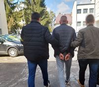 policjanci w ubraniach cywilnych prowadzą zatrzymanego