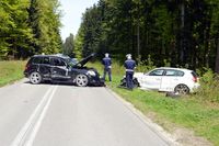 dwaj policjanci w okolicach dwóch samochodów uszkodzonych w wyniku zderzenia wykonują oględziny