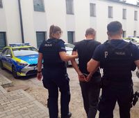 dwuosobowy policyjny patrol doprowadza zatrzymanego do radiowozu