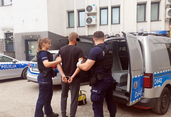 dwuosobowy policyjny patrol doprowadza zatrzymanego do radiowozu