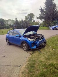 uszkodzony pojazd osobowy po zderzeniu, w tle na poboczu radiowóz