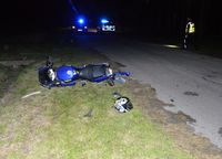 na poboczy leży motocykl, w tle policjant i radiowóz