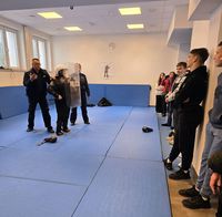 policjant w czasie wizyty uczniów na komendzie prezentuje sprzęt wykorzystywany do działań w pododdziałach zwartych, w który ubrany jest jeden z uczniów