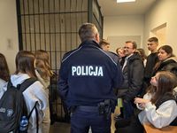 policjant rozmawia z uczniami na korytarzu komendy