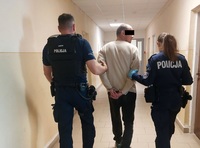 zatrzymany doprowadzany przez dwoje policjantów