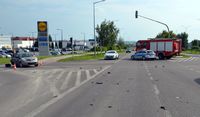 Skrzyżowanie, na którym doszło do zderzenia pojazdów osobowych. Na drodze stoi uszkodzony nissan, radiowóz oraz wóz straży pożarnej.