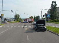 Skrzyżowanie, na którym doszło do zderzenia pojazdów osobowych. Na drodze stoi uszkodzony volkswagen oraz nissan, radiowóz i wóz straży pożarnej. Na ulicy w oddali stoją trzy policjantki.