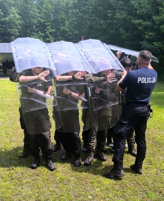 policjant uczy młodzież tworzenia tyraliery