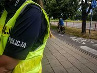 ramię policjanta a w tle na ścieżce rowerowej cyklista