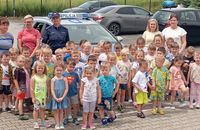 zdjęcie grupowe dzieci i policjantka przed radiowozem