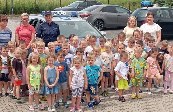 zdjęcie grupowe dzieci i policjantka przed radiowozem