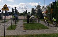 policjant i jeżdżący na rowerach uczniowie na miasteczku rowerowym w czasie egzaminu na kartę rowerową