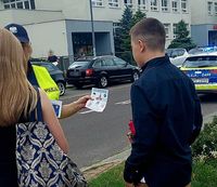 policjantka przekazuje pieszemu ulotkę