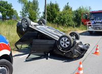 na drodze na dachu leży osobowa Skoda, w tle wóz straży pożarnej