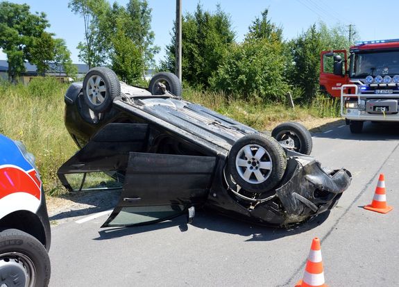na drodze na dachu leży osobowa Skoda, w tle wóz straży pożarnej
