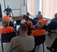 POLICJANT I UCZESTNICY SPOTKANIA PROFILAKTYCZNEGO