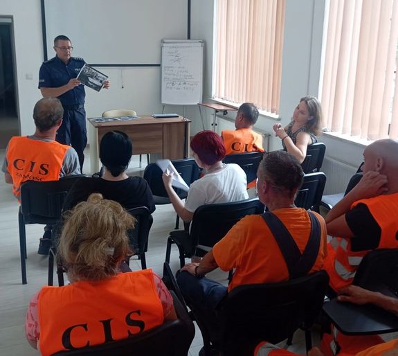 POLICJANT I UCZESTNICY SPOTKANIA PROFILAKTYCZNEGO