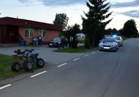 na poboczu drogi stoi quad i dwa radiowozy, w tle budynek