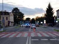 Ulica Partyzantów w Zamościu, miejsce zdarzenia drogowego z udziałem rowerzysty i osobowej Toyoty. Na jezdni leży rower obok stoi Toyota, w tle radiowóz i wóz strażacki.