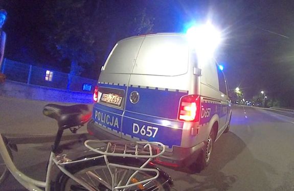 rower na tle radiowozu podczas interwencji w porze wieczornej