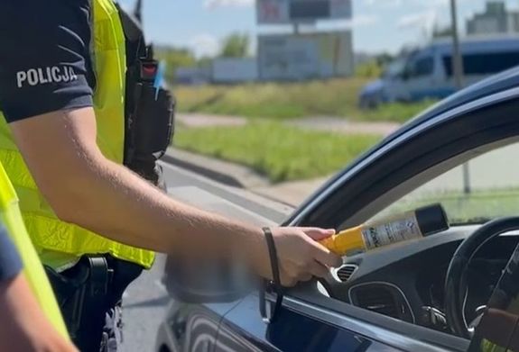 policjant sprawdza stan trzeźwości kierowcy auta