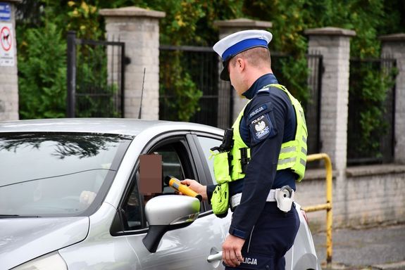 policjant kontrolujący stan trzeźwości kierowcy w samochodzie osobowym