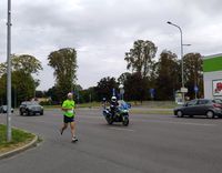 policjant na motocyklu, obok niego biegnie mężczyzna