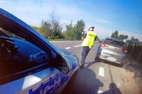 policjant podchodzi do zatrzymanego do kontroli samochodu marki Kia