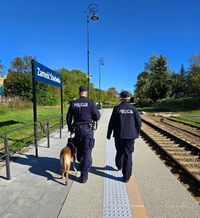 policyjny dwuosobowy patrol z psem służbowym patroluje peron dworca kolejowego