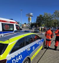 policyjny radiowóz, w tle strażacy w czasie pokazu gaszenia pożaru