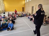 policjantka w czasie spotkania profilaktycznego mówi do siedzących na podłodze dzieci