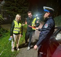 policjant przekazuje kobiecie i mężczyźnie odblaskowe opaski